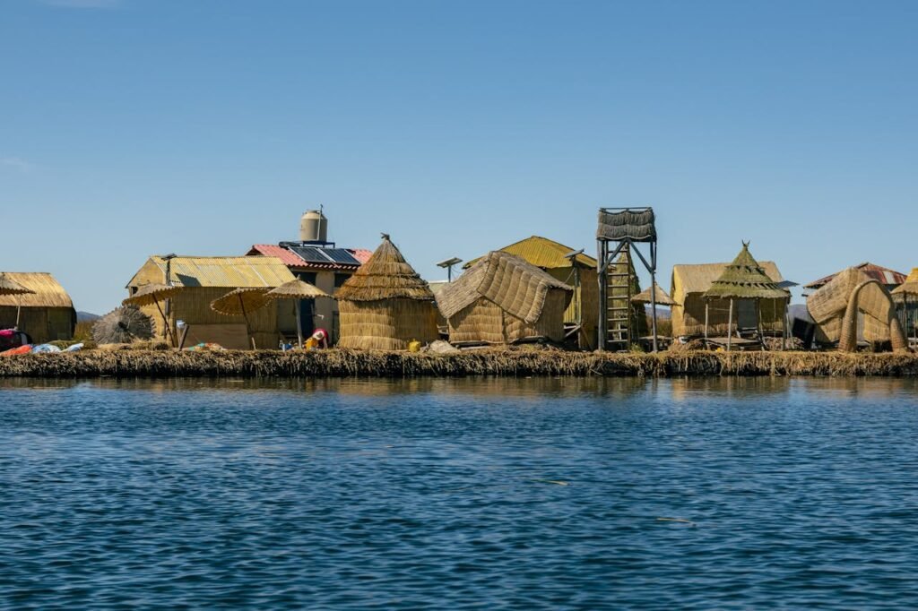 Explore traditional reed island homes on Lake Titicaca, Peru, against a serene water backdrop.